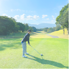 製作者がゴルフ場でゴルフクラブを持って構えている写真